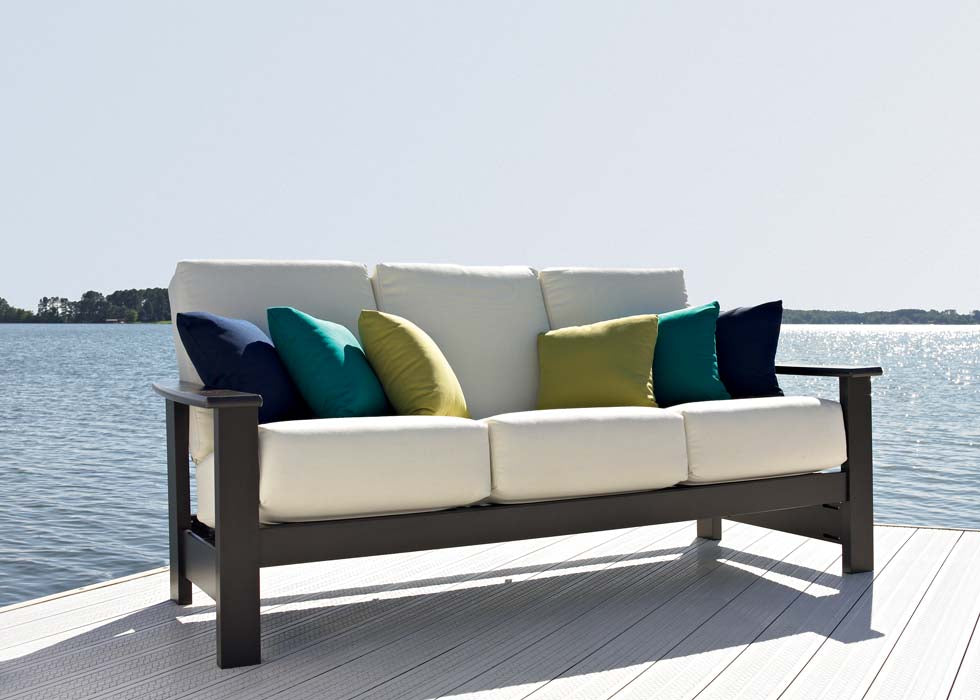 Photo of a club sofa on the patio with water in the background.