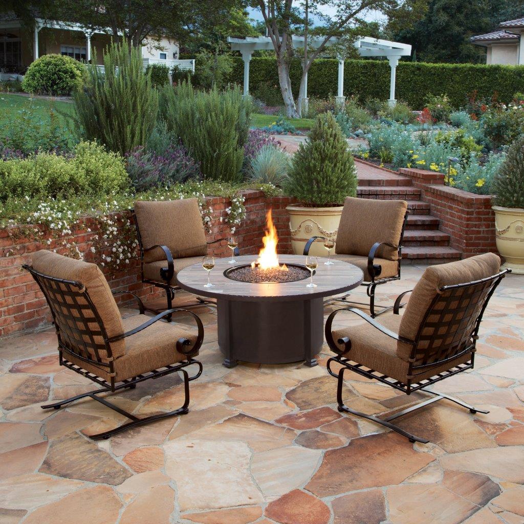 Photo of Club Lounge chair set and firepit table on stone patio with lush landscaping