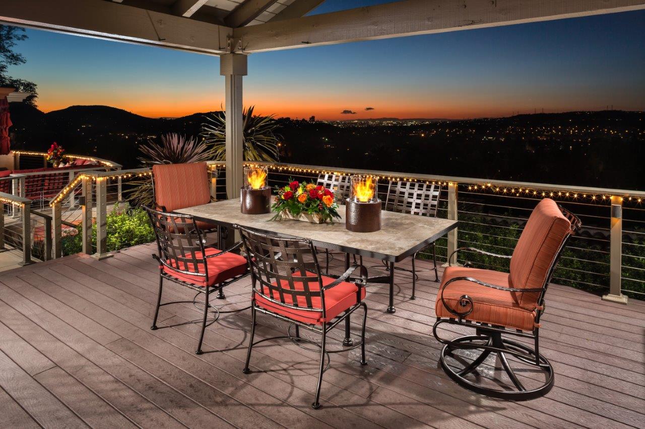 Photo of Dining table set on deck with overhang during sun set.
