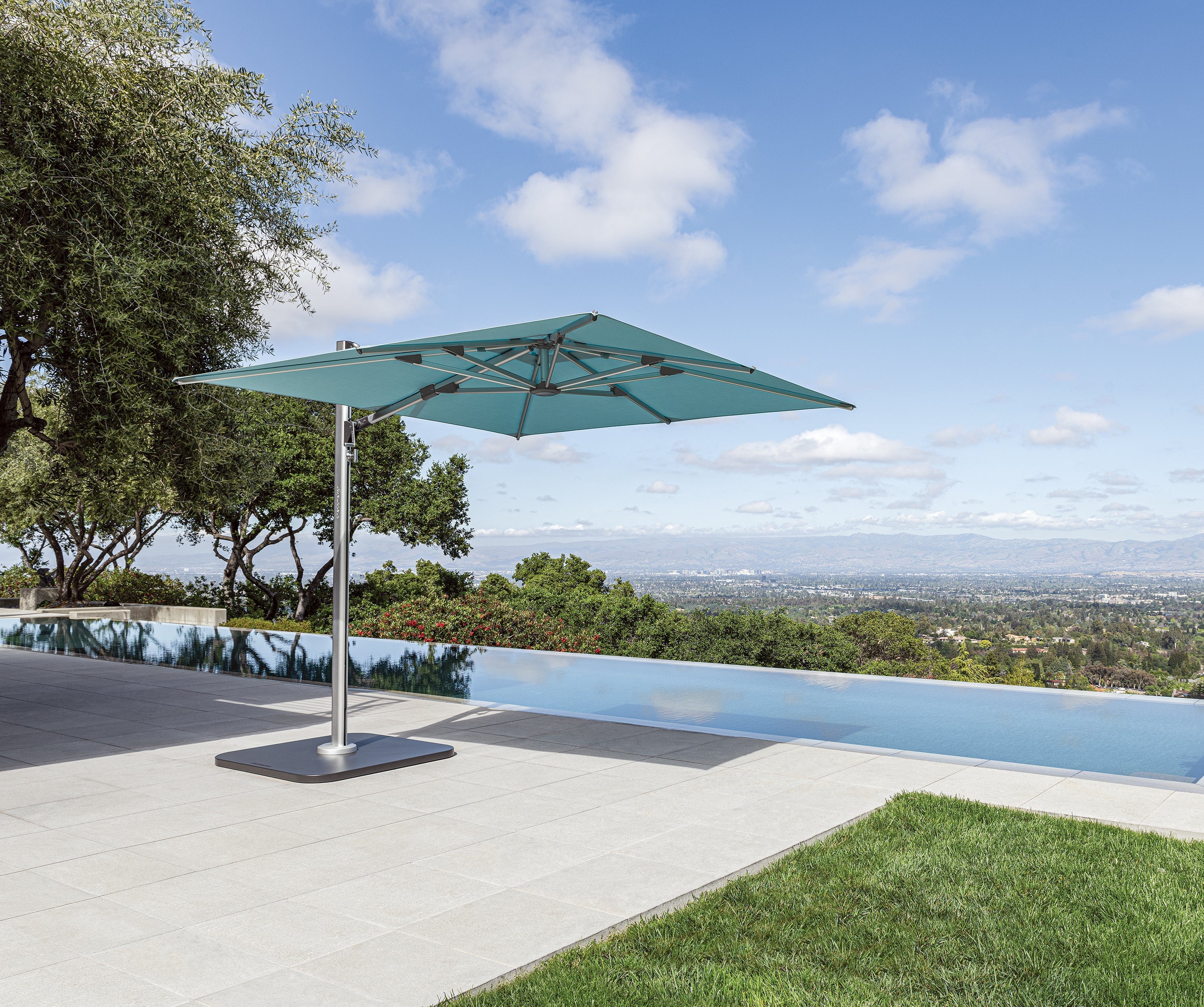 Photo of a cantilever umbrella on the patio next to pool with an infinity view