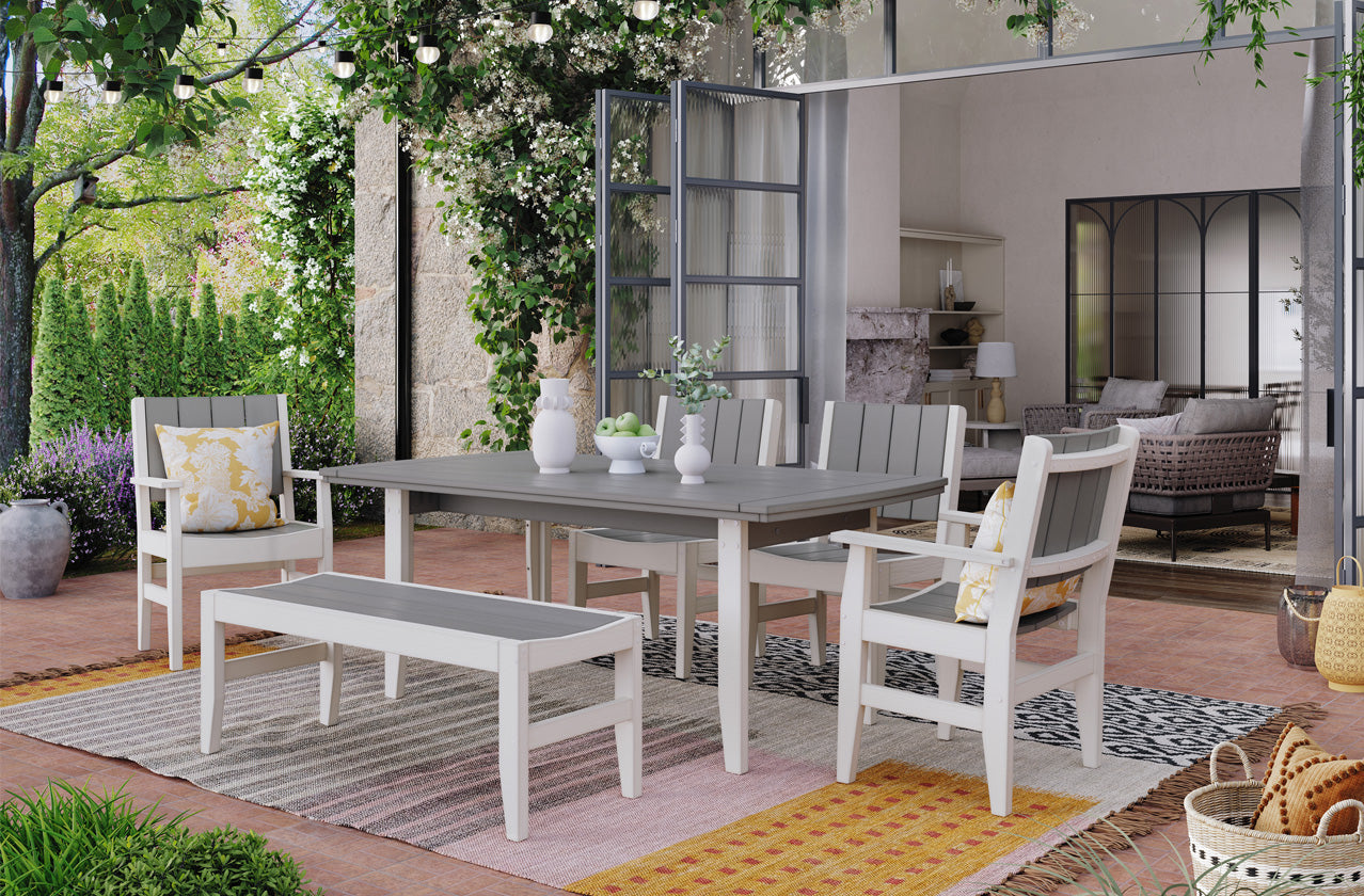 Outdoor patio with white and gray dining set, surrounded by greenery.